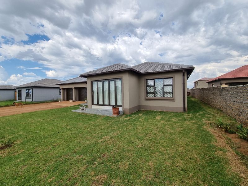A well-maintained single-story residential home featuring a tiled roof, neutral exterior paint, aluminium window frames with security bars, and a spacious front lawn.