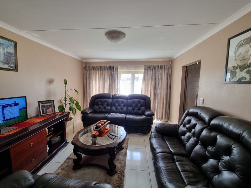 A comfortable living room featuring neutral wall tones, tiled flooring, and natural light through window curtains.