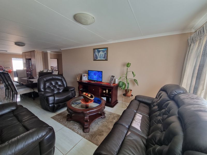 An open-plan living and dining area featuring neutral wall tones and tiled flooring, providing a functional and connected space for daily living.