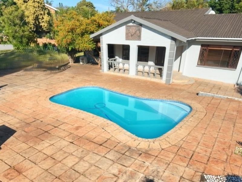 Rear exterior view featuring a swimming pool, paved patio area, and a covered patio attached to the main house structure.