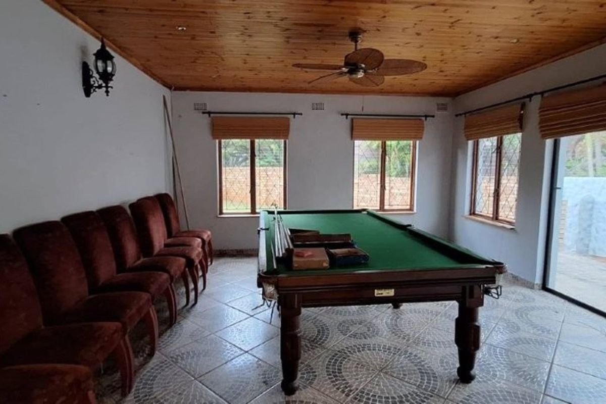 Spacious living area featuring a timber ceiling, ceiling fan, tiled flooring, and large windows, providing a versatile space for recreation or relaxation.