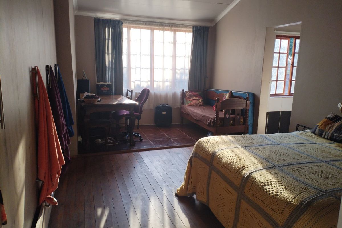 Spacious bedroom featuring a combination of timber and tiled flooring, large window for natural light, and direct access to an adjacent area.