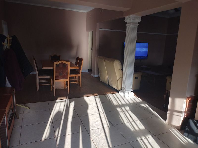 Open plan living and dining area featuring a decorative column, mixed flooring types, and coved cornicing in a lived-in condition.