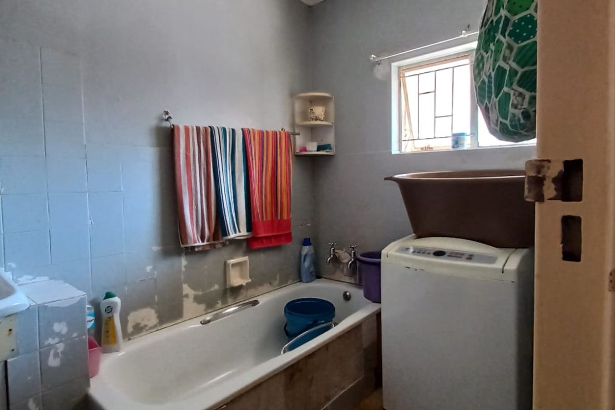A functional bathroom featuring a bathtub and tiled walls, currently showing signs of wear and requiring cosmetic updates to improve its overall condition.