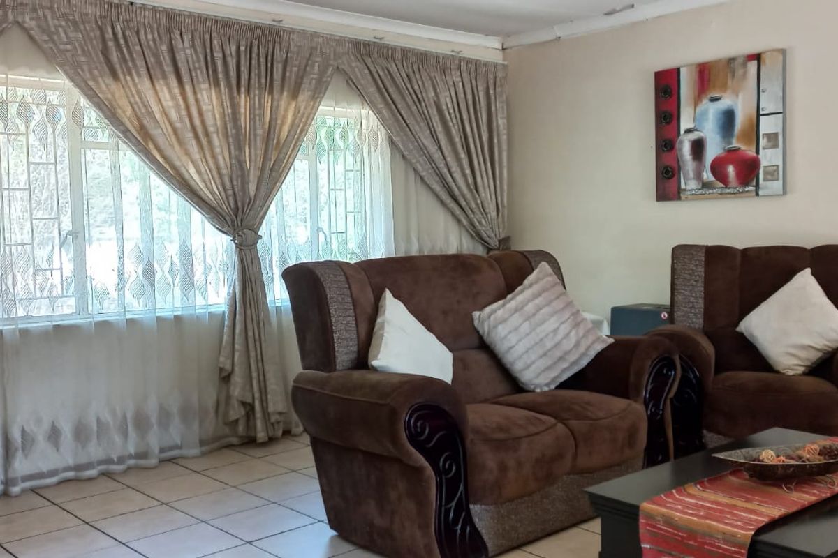 A comfortable living room featuring tiled flooring and large windows fitted with security bars, offering a bright and functional space.