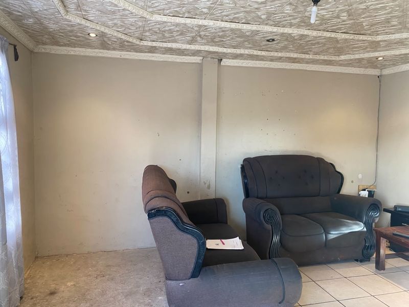 Living room featuring decorative ceiling tiles, recessed lighting, and tiled flooring. The walls require cosmetic attention and repainting.