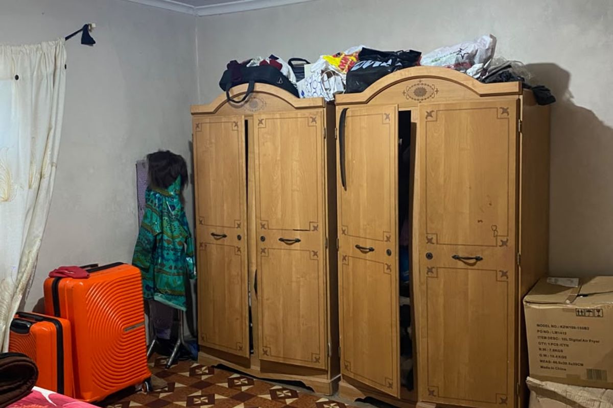 A bedroom featuring built-in wooden wardrobes and patterned floor covering, requiring cosmetic updates to improve the overall finish and appeal.