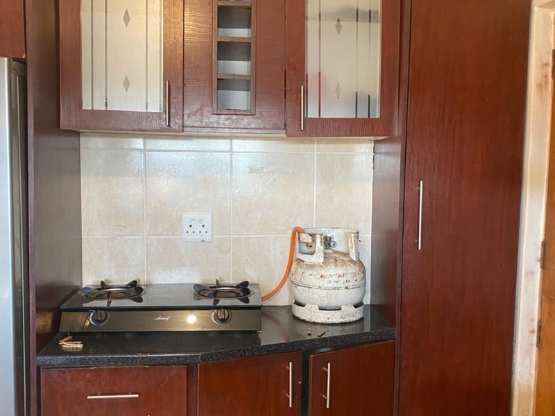 Compact kitchen featuring dark wood cabinetry, granite countertops, and a built-in gas hob with tiled backsplash.