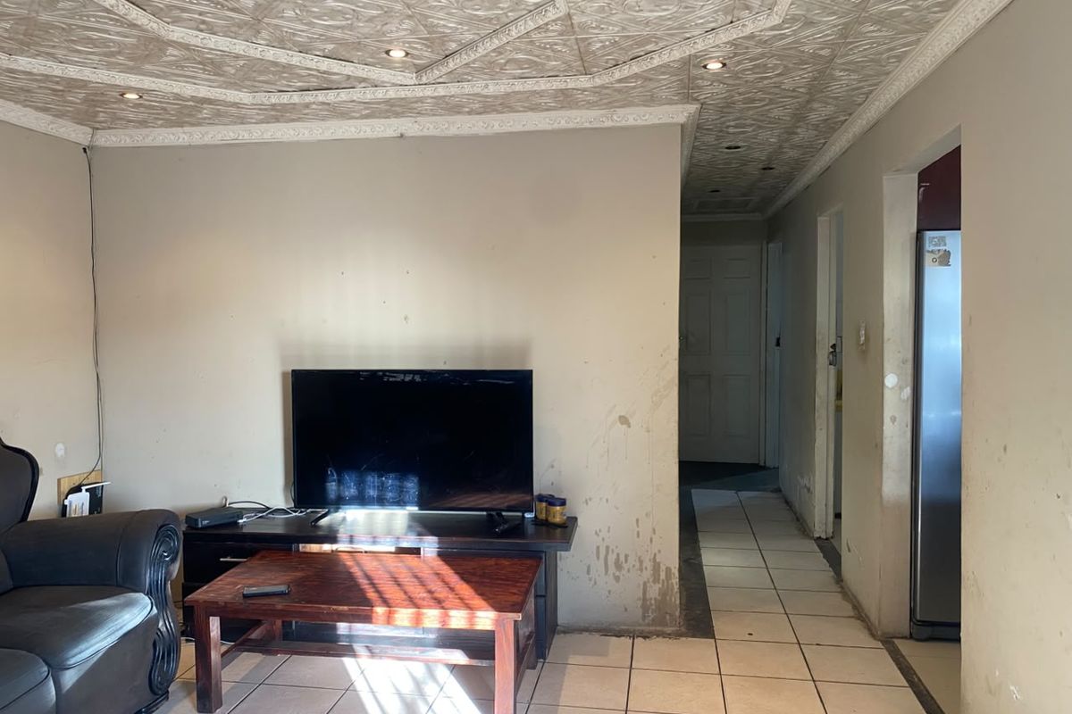 Living area featuring decorative ceiling tiles, recessed lighting, and ceramic floor tiles, requiring cosmetic wall repairs and fresh paint to improve the overall condition.