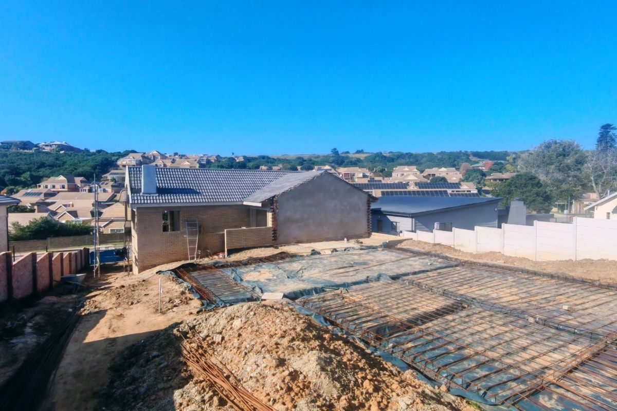 Aerial view of a residential construction site showing a prepared concrete foundation with reinforcing steel mesh and surrounding boundary walls.