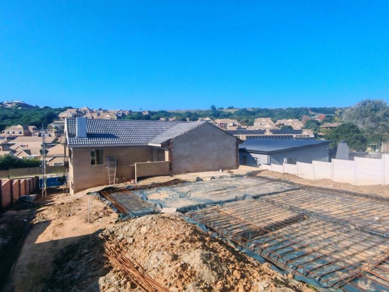 Aerial view of a residential construction site showing a prepared concrete foundation with reinforcing steel mesh and surrounding boundary walls.