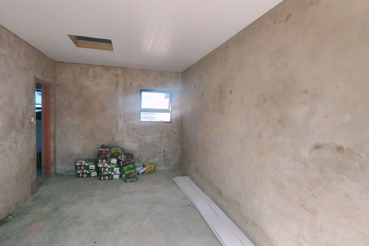 An unfinished bedroom space featuring raw plastered walls, concrete flooring, and a white ceiling with an access hatch.