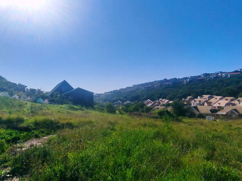 A wide-angle view of the vacant residential land, showcasing the surrounding landscape, natural vegetation, and neighboring residential developments.