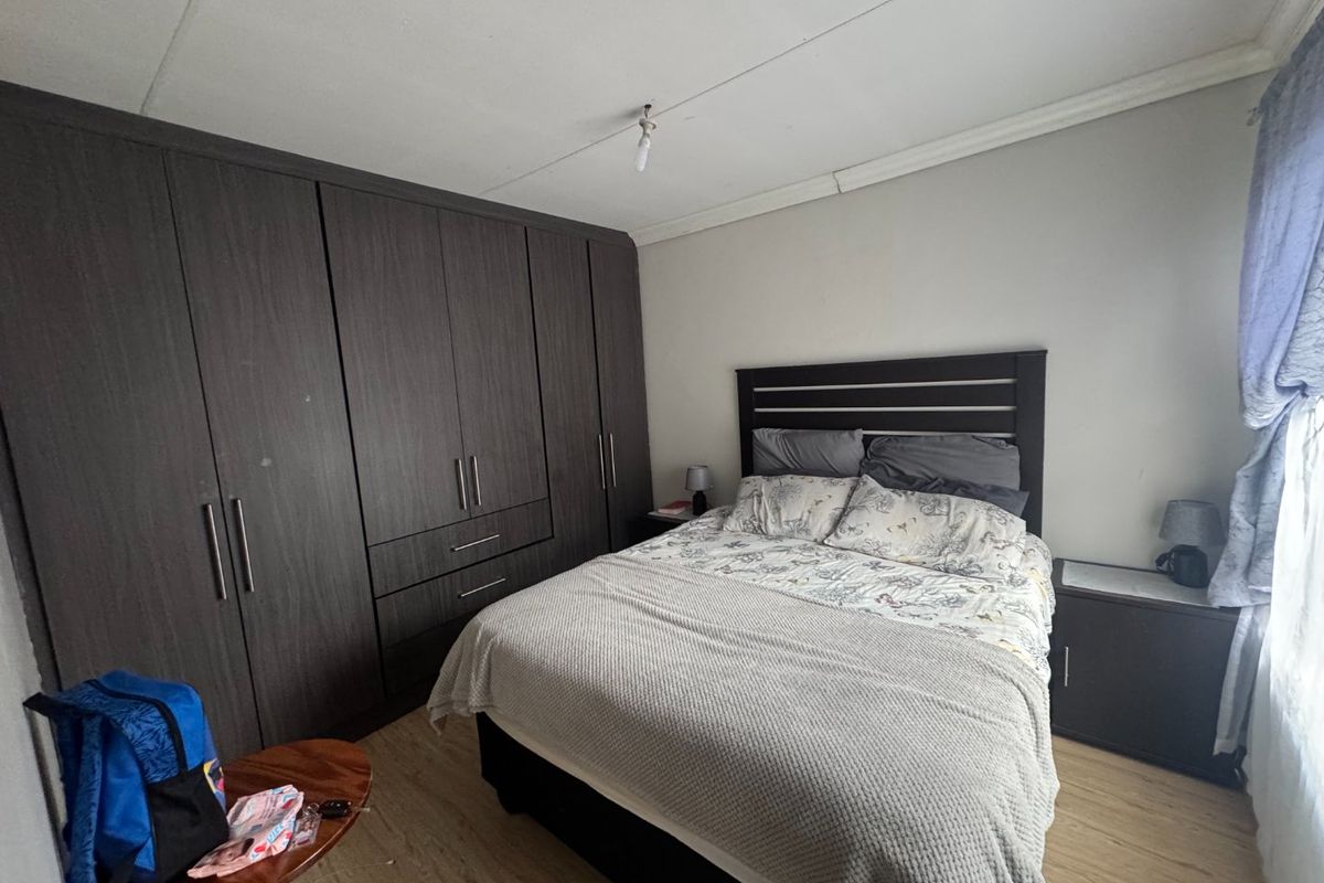 A bedroom featuring dark wood built-in cupboards, laminate flooring, and a coved ceiling, providing functional storage and a neutral base.
