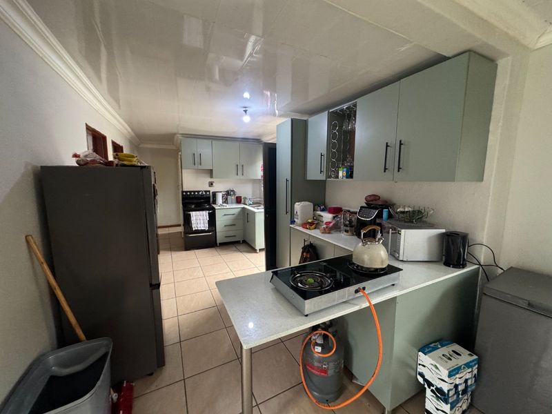 A functional kitchen featuring built-in cabinetry, tiled flooring, and a gas hob setup, offering a practical layout for daily meal preparation.