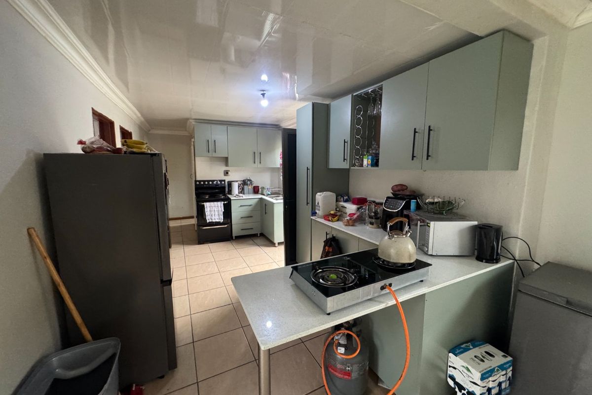 A functional kitchen featuring built-in cabinetry, tiled flooring, and a gas hob setup, offering a practical layout for daily meal preparation.