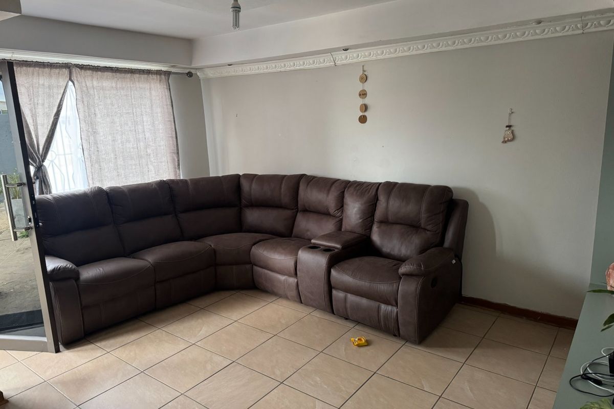 A living room featuring ceramic floor tiles, decorative ceiling cornicing, and a sliding glass door providing access to the exterior.