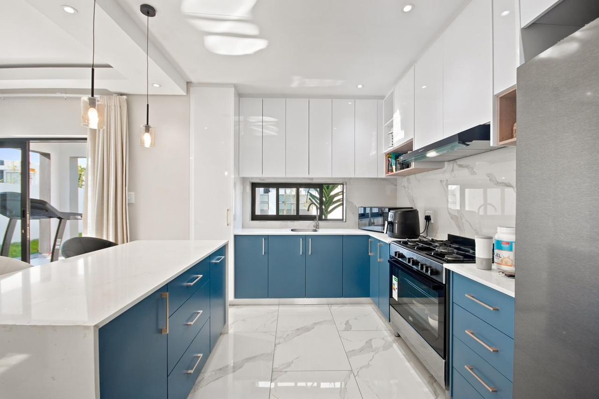 Modern kitchen featuring blue and white cabinetry, quartz countertops, marble-look floor tiles, and high-end built-in appliances.