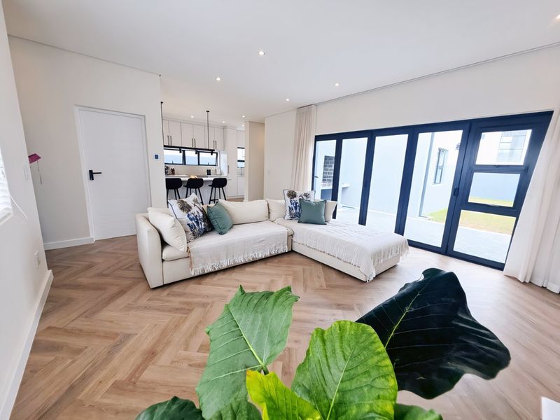 Modern open-plan living area featuring herringbone timber flooring, recessed lighting, and large sliding doors providing seamless access to the outdoor patio.