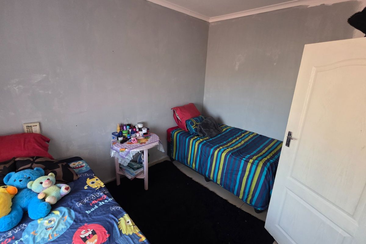 A bedroom featuring grey painted walls with visible finish inconsistencies and a standard interior panel door.