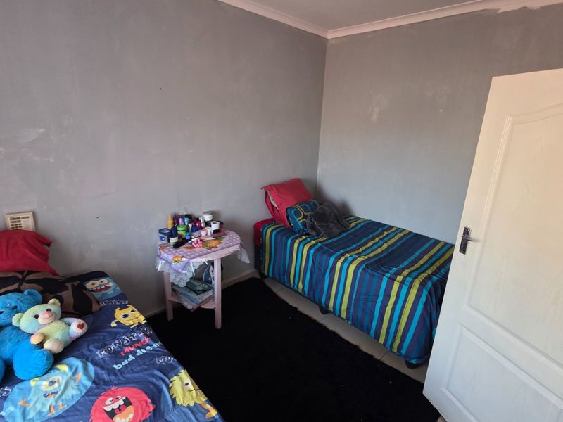 A bedroom featuring grey painted walls with visible finish inconsistencies and a standard interior panel door.