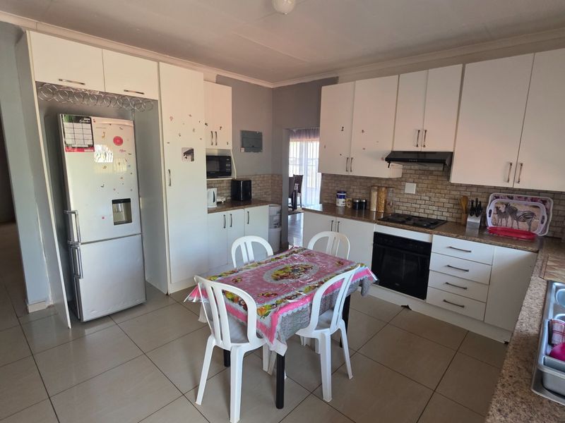 A functional kitchen featuring white built-in cabinetry, a tiled backsplash, integrated oven and hob, and tiled flooring throughout.