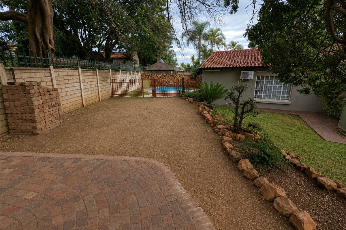 Rear garden area featuring a paved patio, gravel landscaping, perimeter walling, and access to a swimming pool.