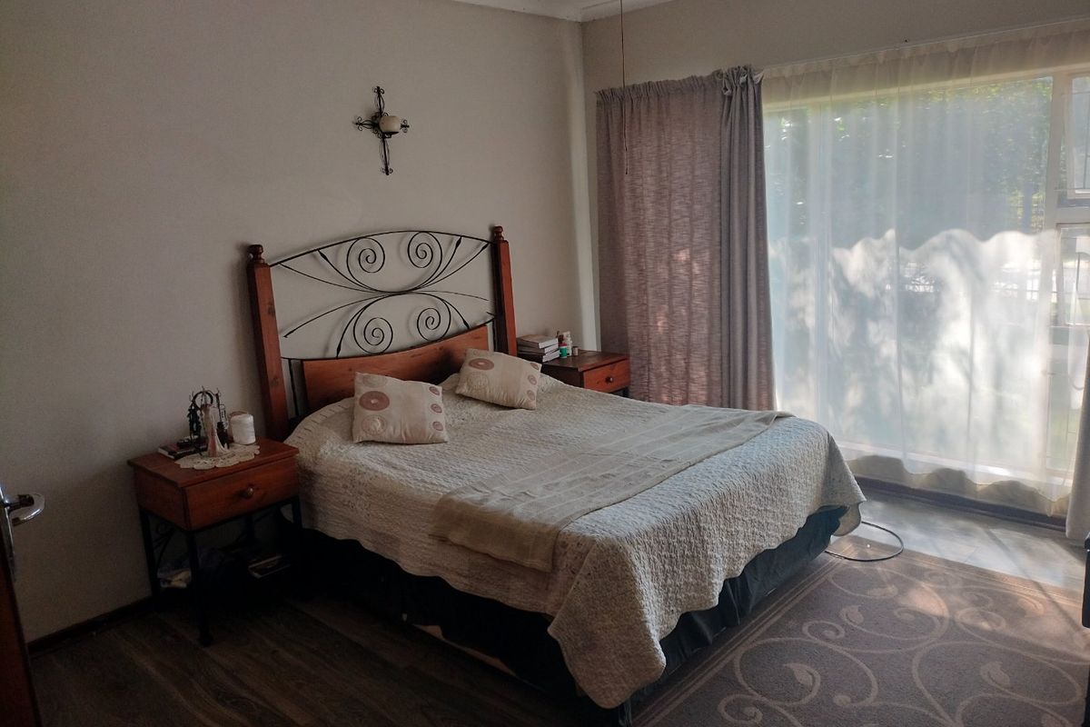 A well-lit bedroom featuring laminate flooring and a large sliding glass door providing natural light.
