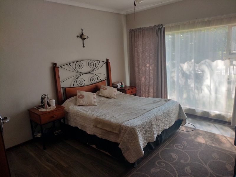 A well-lit bedroom featuring laminate flooring and a large sliding glass door providing natural light.