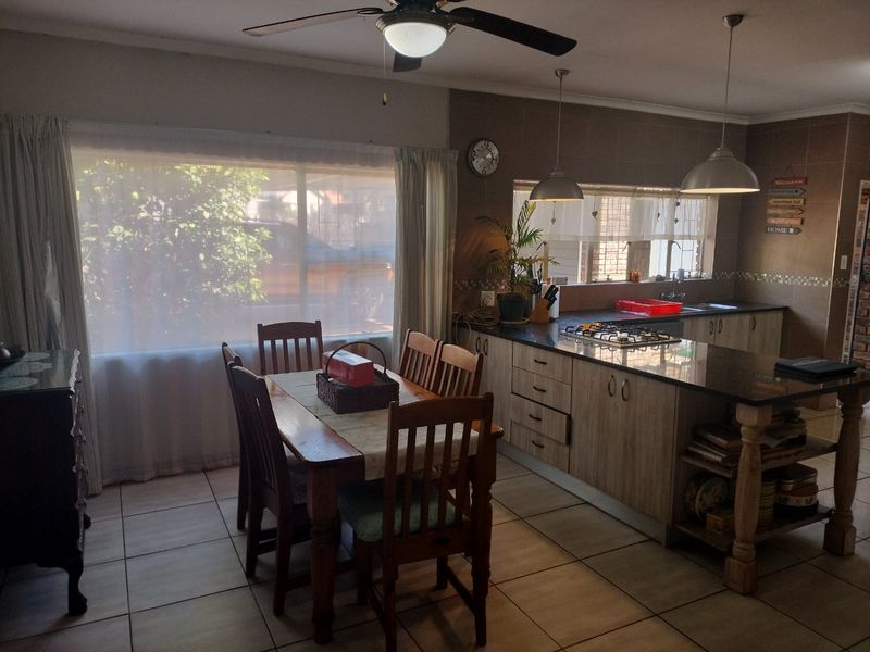 Open-plan kitchen and dining area featuring a central island with granite countertops, built-in gas hob, and tiled flooring throughout.