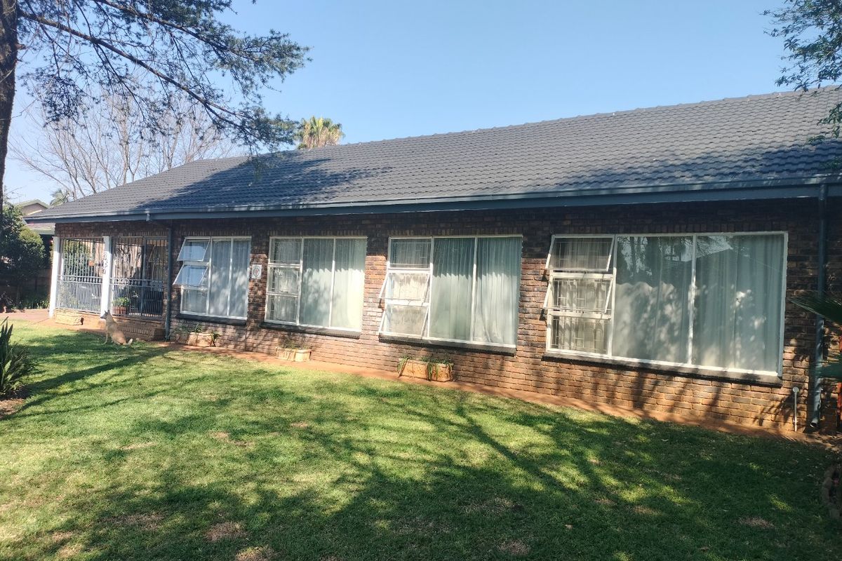 A view of the rear exterior of the house featuring a face brick facade, tiled roof, and large windows overlooking a lawn.