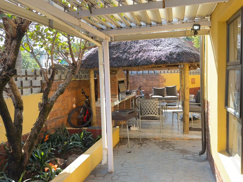Covered outdoor patio area featuring a traditional thatched lapa and a built-in braai, perfect for outdoor entertaining and relaxation.