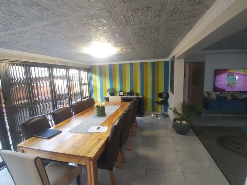 Open plan dining area featuring tiled floors, patterned ceiling tiles, and large sliding glass doors leading to an outdoor space.