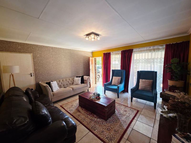 A comfortable living room featuring tiled flooring, textured wallpaper, and a central ceiling light fixture, providing a functional and inviting space.