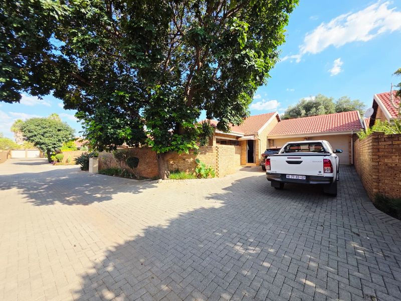 Front exterior view of a townhouse featuring a paved driveway, facebrick facade, and a double garage.