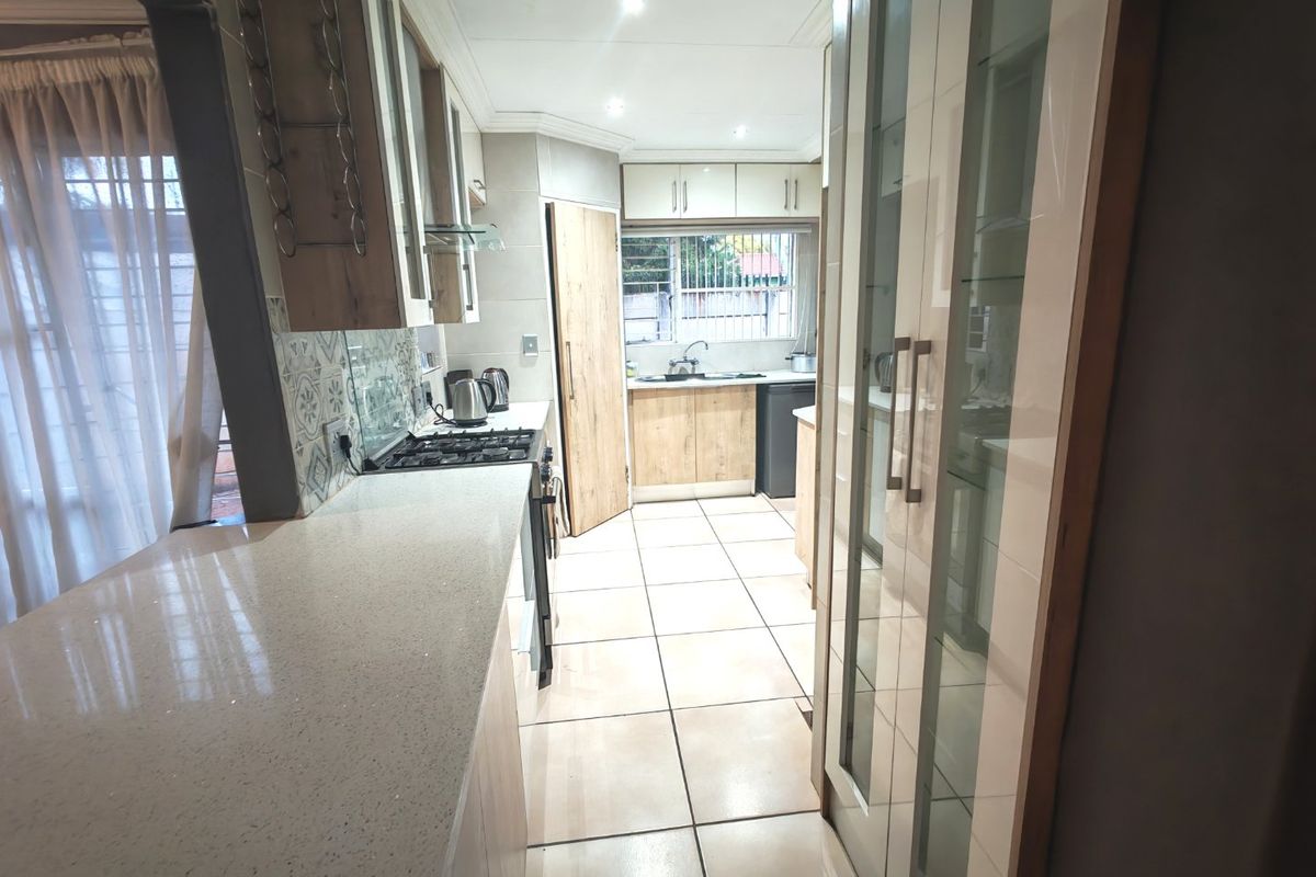 Modern kitchen featuring stone countertops, ample built-in cabinetry, gas cooktop, and tiled flooring, offering a functional and well-lit workspace.