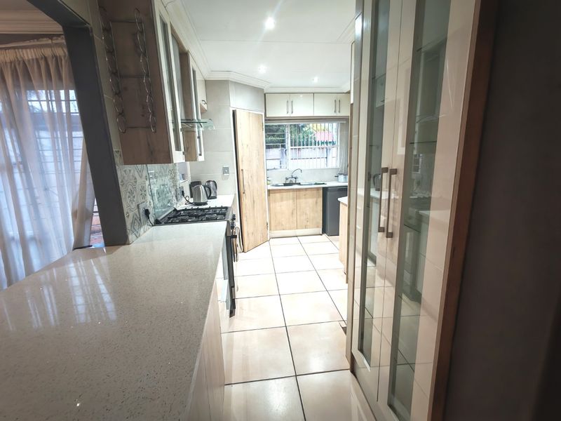 Modern kitchen featuring stone countertops, ample built-in cabinetry, gas cooktop, and tiled flooring, offering a functional and well-lit workspace.