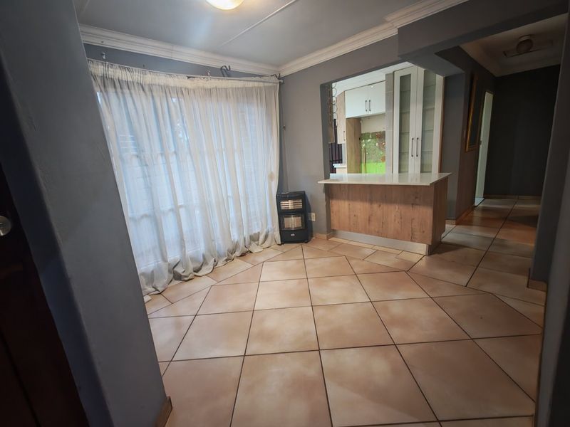 Open plan living area featuring tiled flooring, coved cornicing, and a breakfast bar connecting to the kitchen space.
