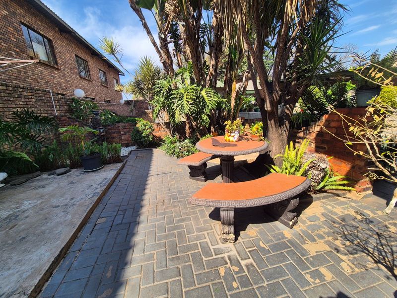 A rear garden area featuring brick paving, mature trees, and face brick boundary walls, providing a private outdoor space.