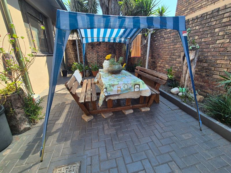 A paved outdoor patio area enclosed by a brick boundary wall, providing a private space for outdoor dining and relaxation.