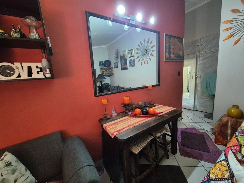 A living area featuring tiled flooring, built-in storage cupboards, and a wall-mounted mirror with integrated vanity lighting.