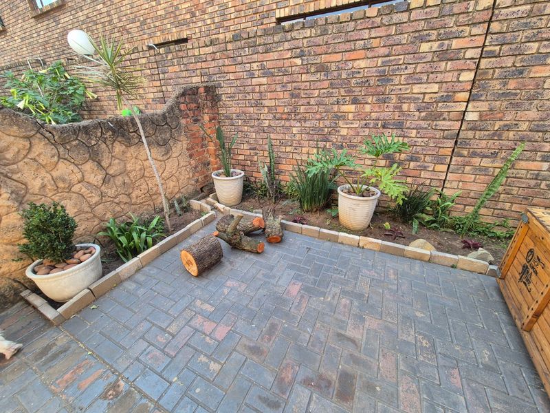 A private rear courtyard area featuring brick paving, a solid brick boundary wall, and a decorative stone-clad feature wall.