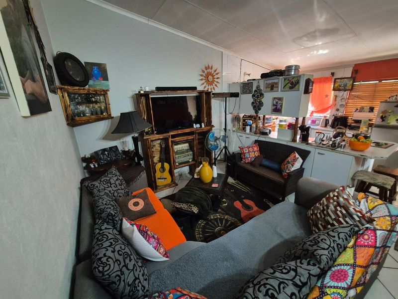 Open plan living area featuring a combined lounge and kitchen space with tiled flooring and functional cabinetry.