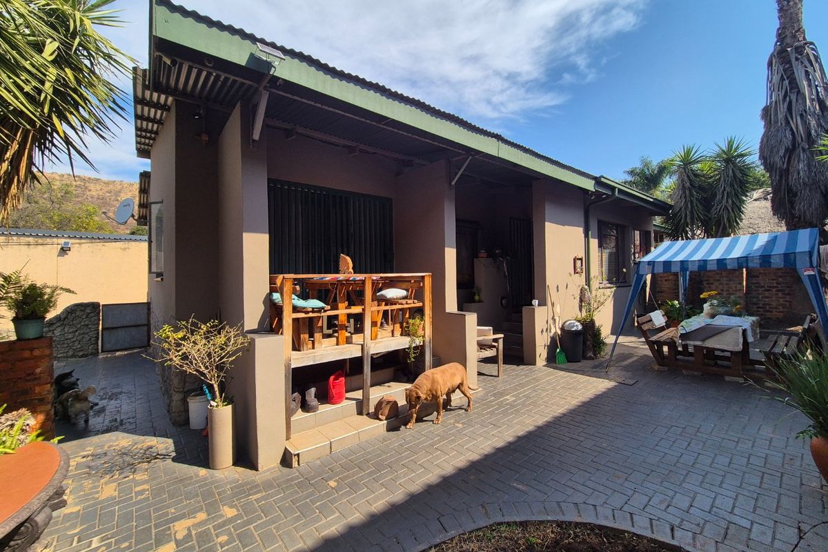 Rear view of the property featuring a covered veranda and a paved patio area with brick paving.