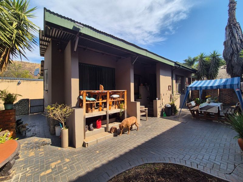 Rear view of the property featuring a covered veranda and a paved patio area with brick paving.