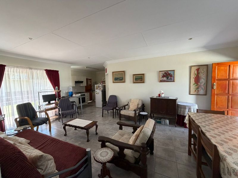 Spacious open-plan living and dining area featuring tiled flooring, recessed lighting, and an integrated kitchen space with functional cabinetry.