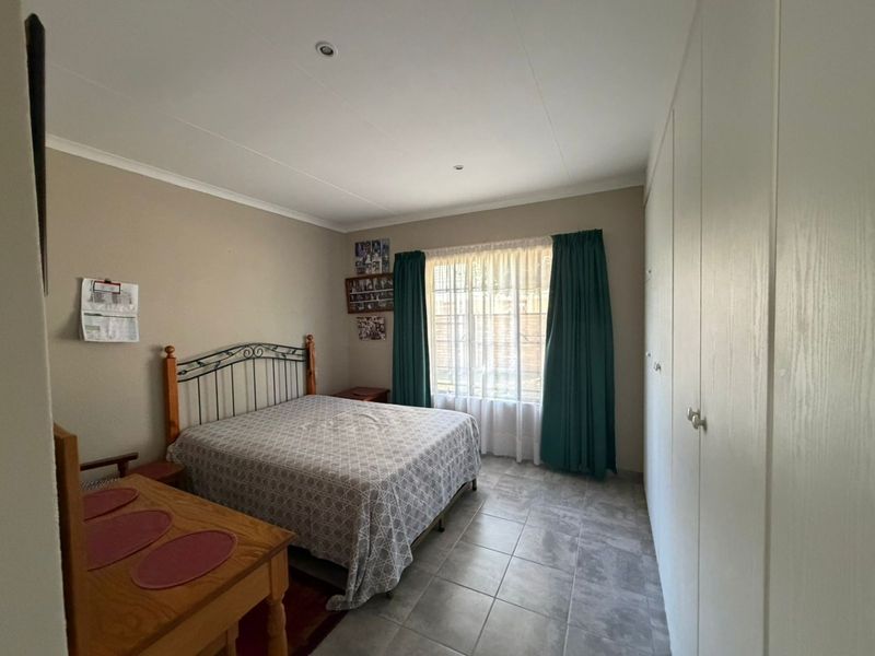 A functional bedroom featuring tiled flooring, recessed ceiling lighting, and ample built-in cupboard storage space.