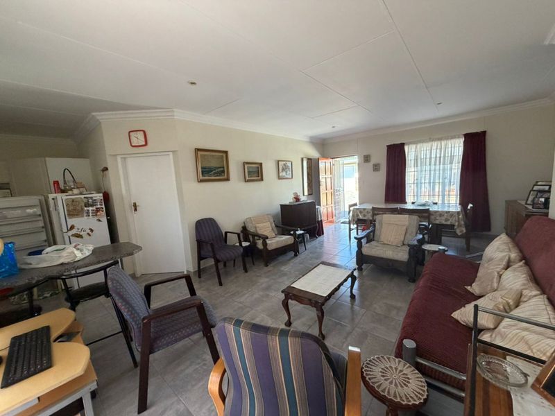 Spacious open-plan living and dining area featuring neutral wall tones, tiled flooring, and recessed ceiling lighting, offering a versatile layout for family living.