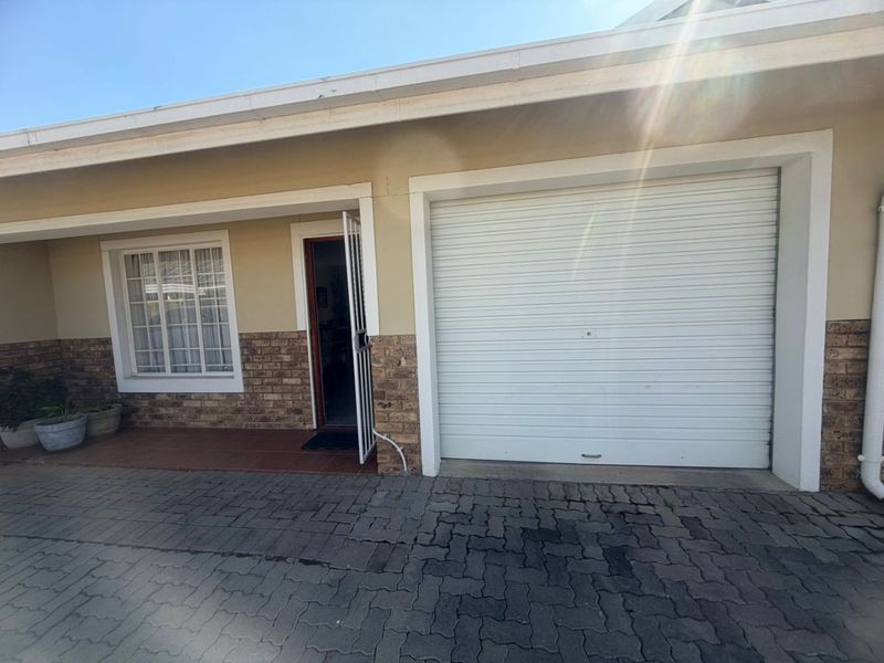 Front exterior view of the townhouse featuring a roller garage door, brick facade detailing, and a paved driveway entrance.