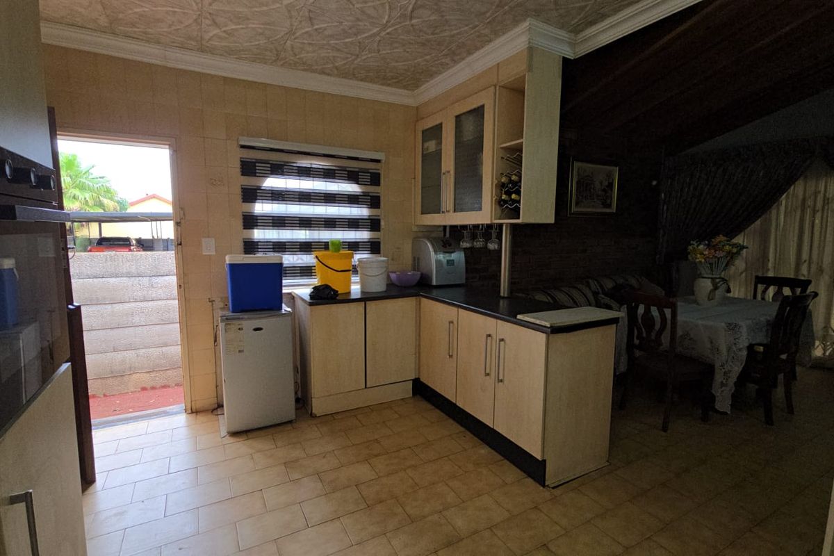 A functional kitchen area featuring built-in cabinetry, tiled flooring, and a built-in oven, with direct access to the exterior.